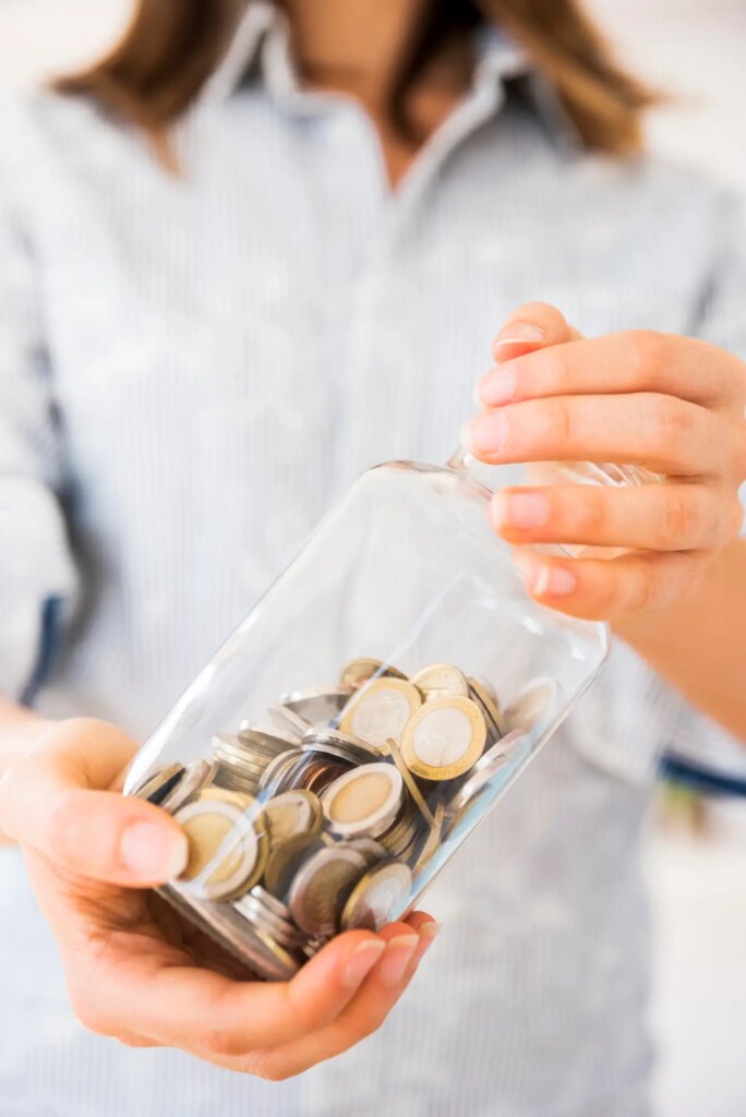 Mulher segurando pote de dinheiro - poupança e investimentos